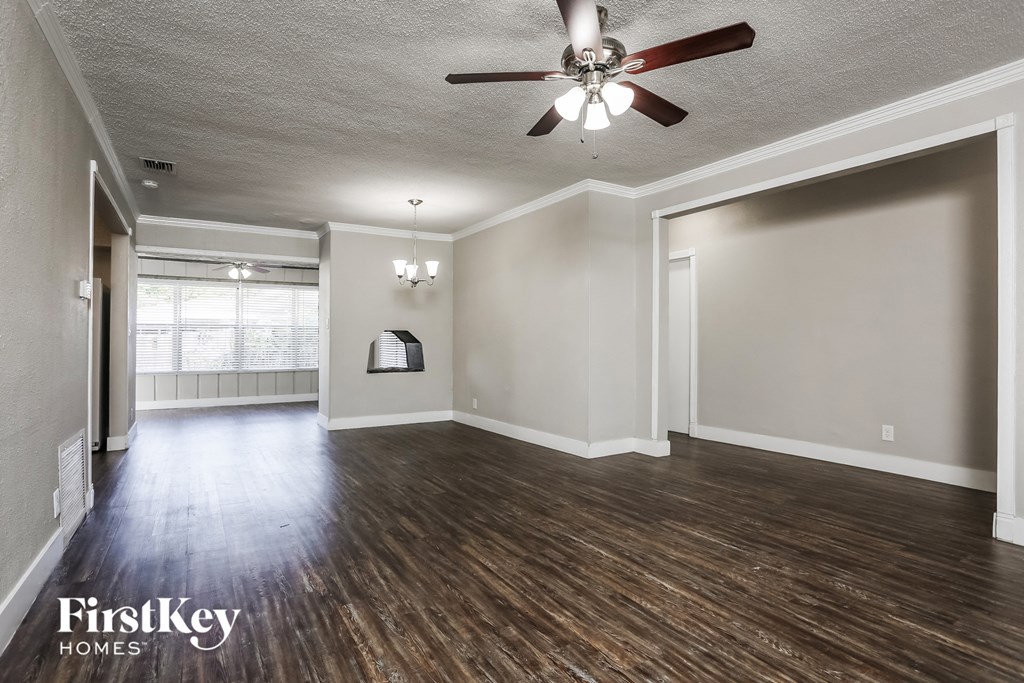 an empty living room with wood floors and a ceiling fan