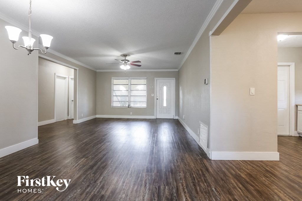 an empty living room with wood floors and a ceiling fan
