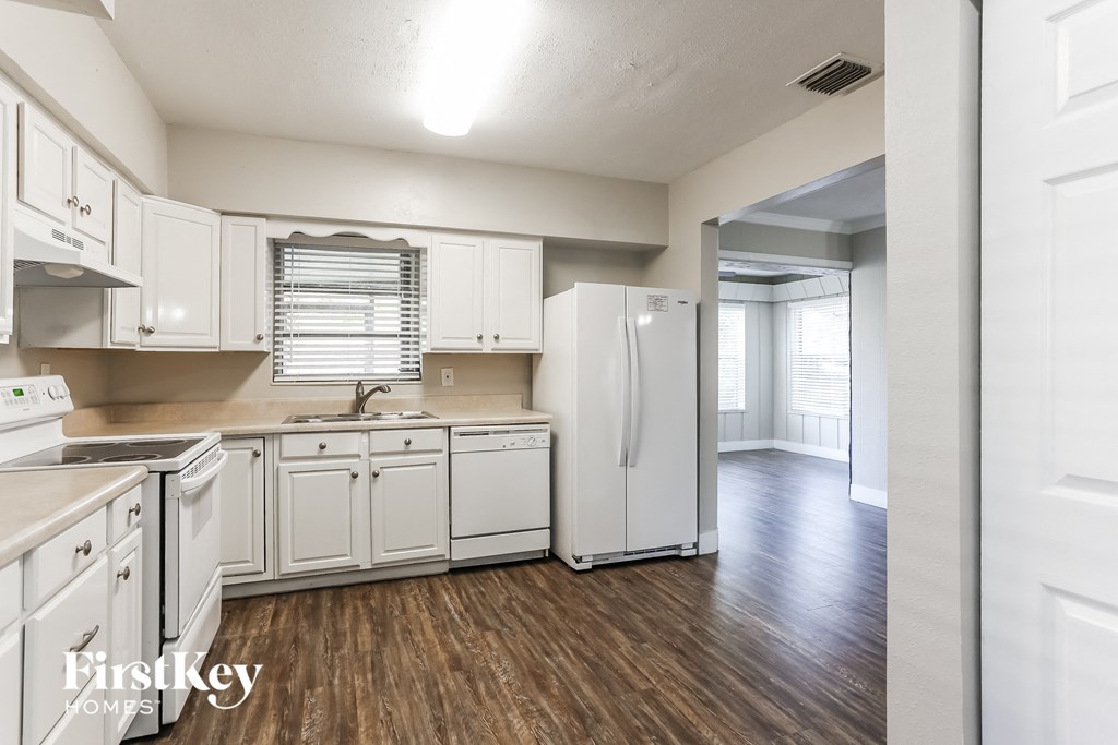 an empty kitchen with white cabinets and a white refrigerator