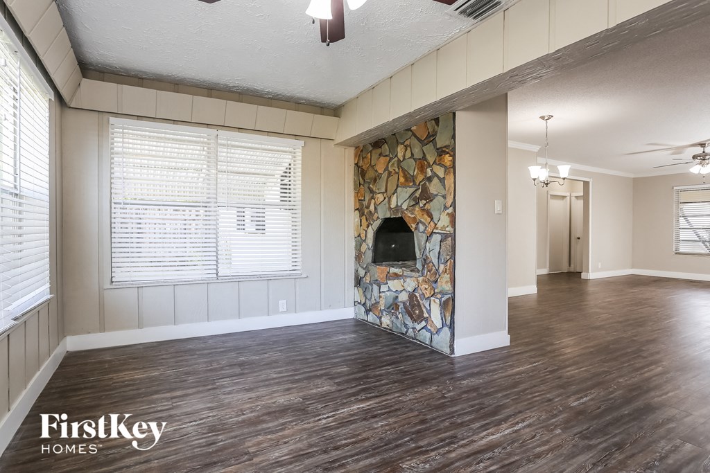 an empty living room with a fireplace and wood flooring