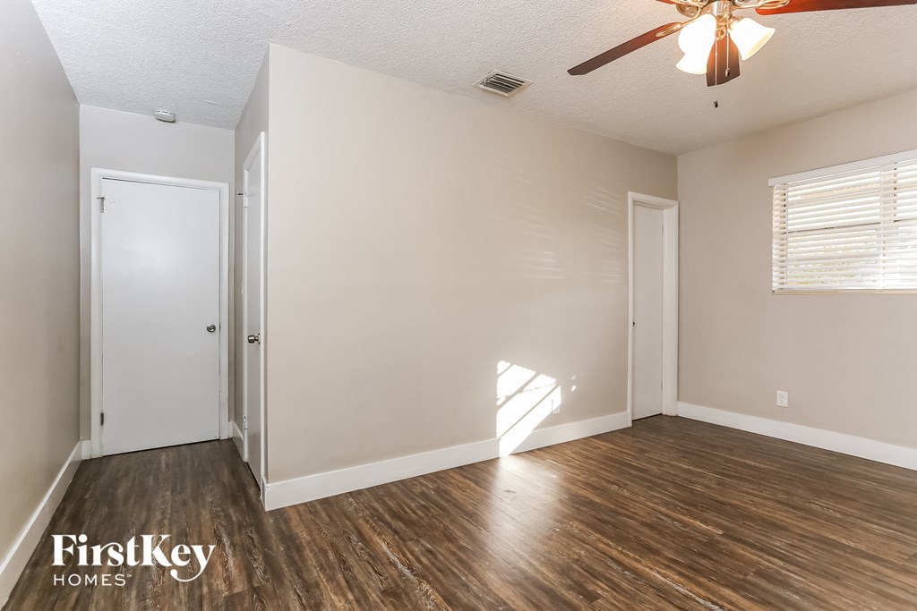 the living room of an empty house with wooden floors and a ceiling fan