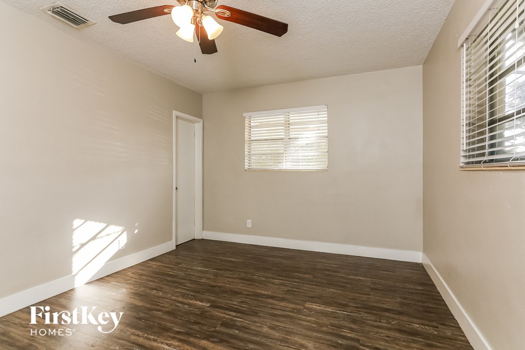 an empty room with a ceiling fan and a window