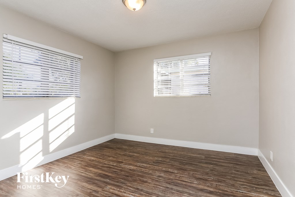 the living room of an empty house with wood flooring and two windows