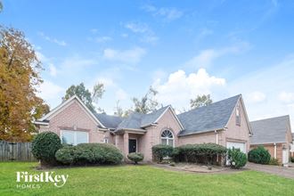 a brick house with a green lawn and a blue sky