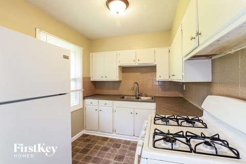 A kitchen with a white gas stove and a white refrigerator.