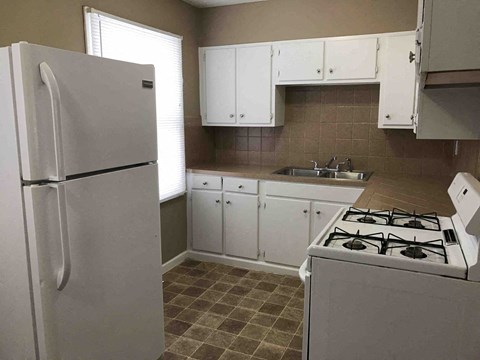 A kitchen with a white refrigerator, white cabinets, and a white gas stove.