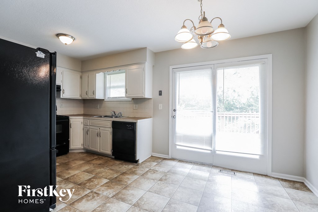 A kitchen with a black refrigerator and white cabinets.