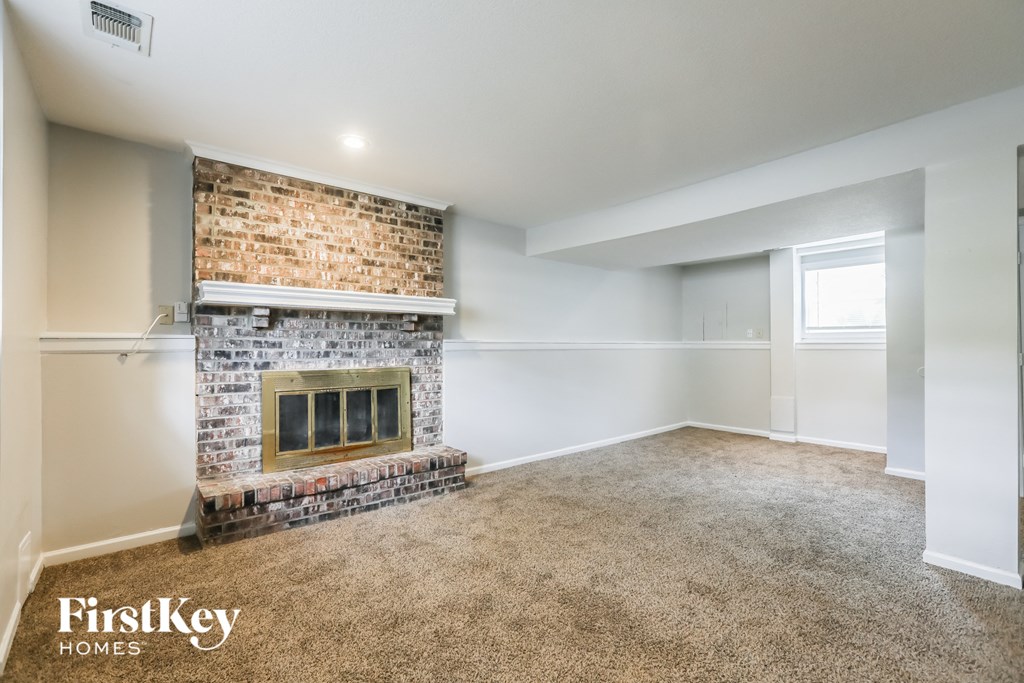 A room with a brick fireplace and a carpeted floor.