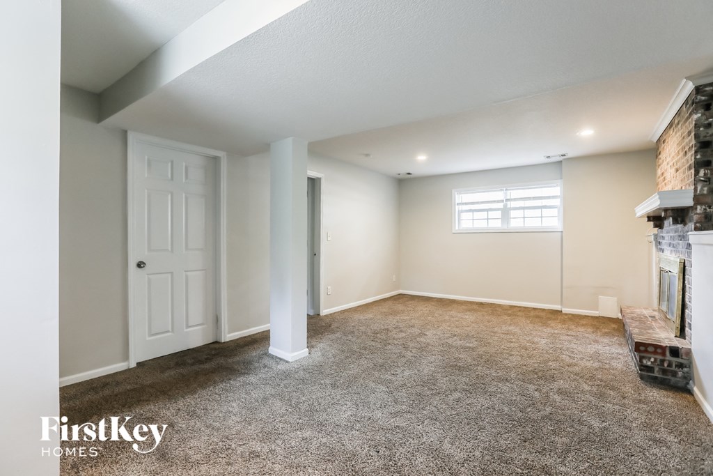 A room with a carpeted floor and a window with blinds.
