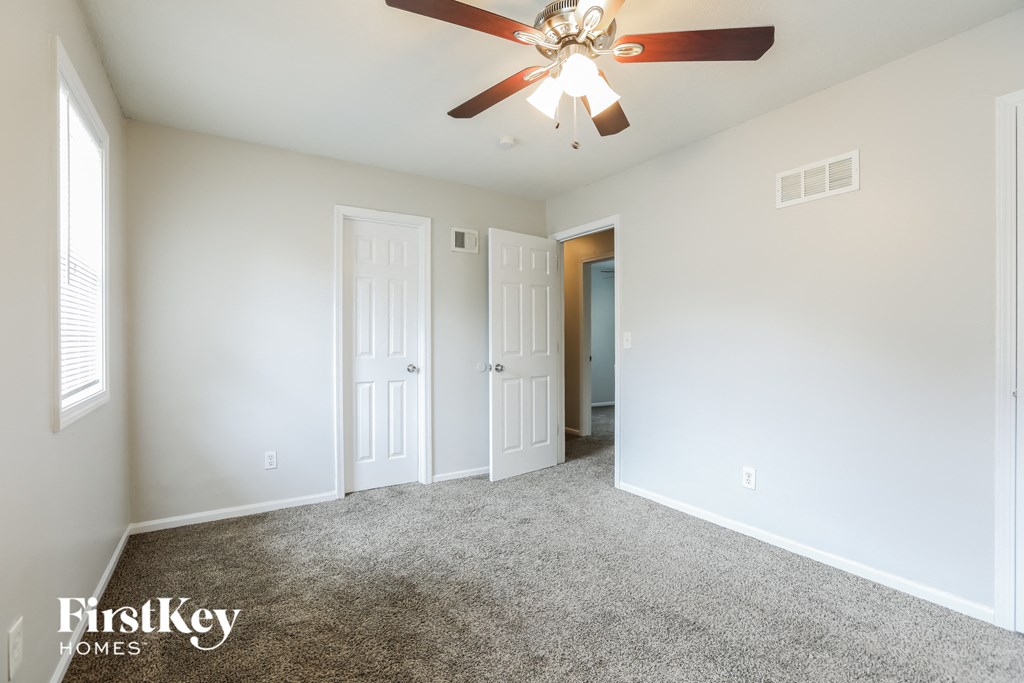 A room with a ceiling fan and three doors.