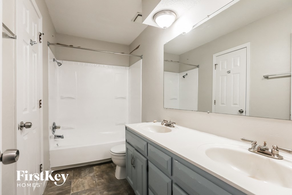 A white bathroom with a double sink and a walk-in shower.