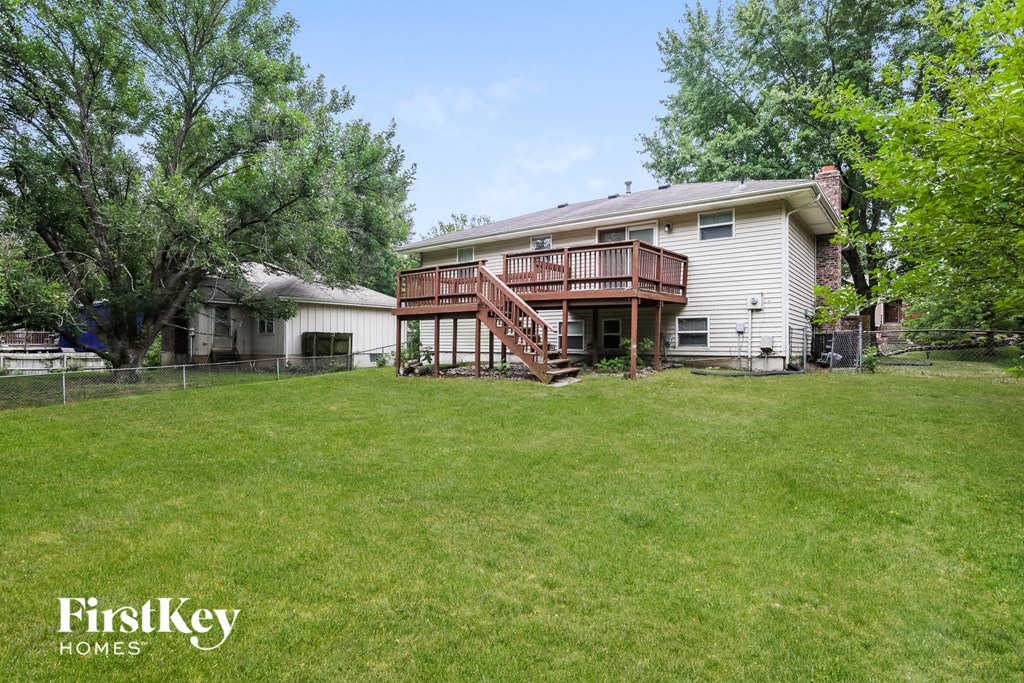 A house with a deck and a tree in front of it.