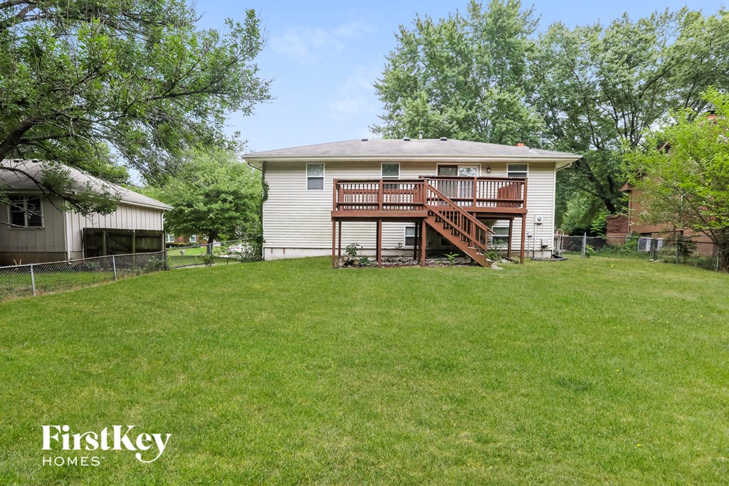 A white house with a balcony and a tree in the front yard.