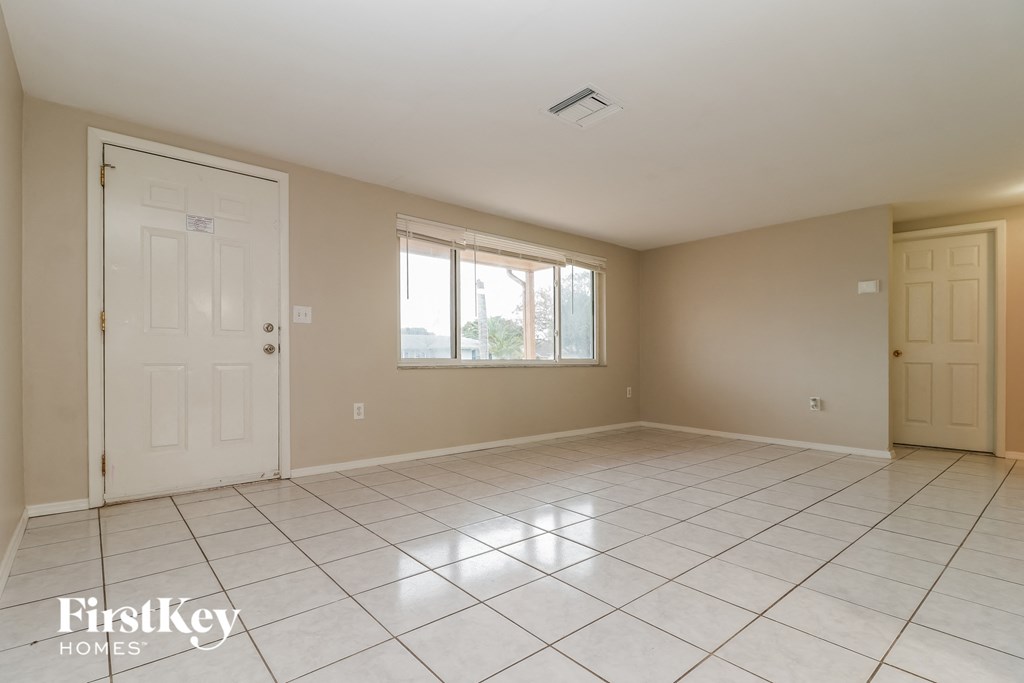 an empty living room with a white tile floor and a white door