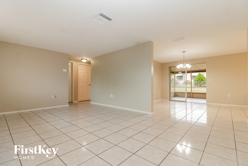 a spacious living room with tiled flooring and a door to the kitchen