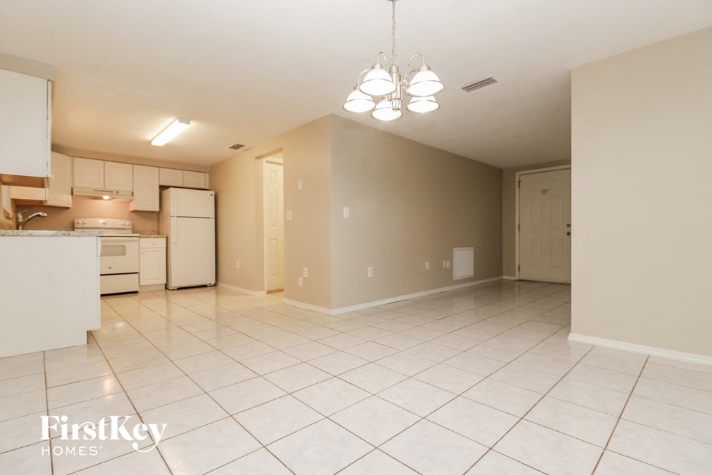 a large kitchen and living room with white tile flooring and white appliances