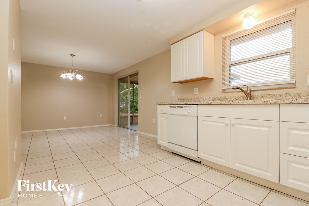 a kitchen with white cabinets and tiled flooring and a sink and counter top