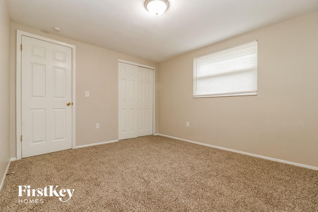 a bedroom with carpet and two doors and a window