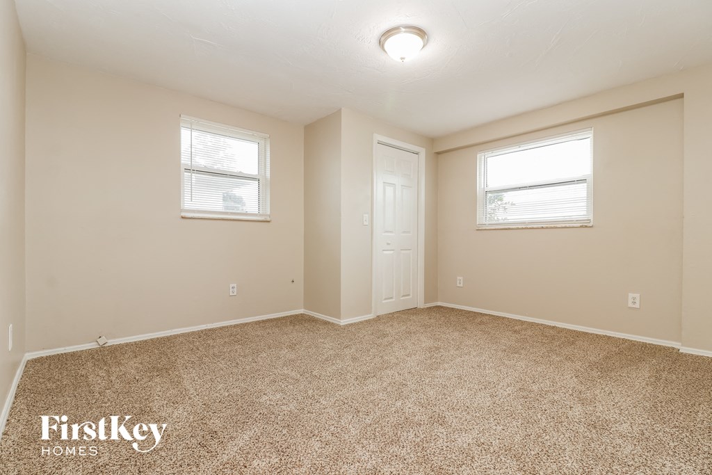 the spacious living room with carpeting and two windows