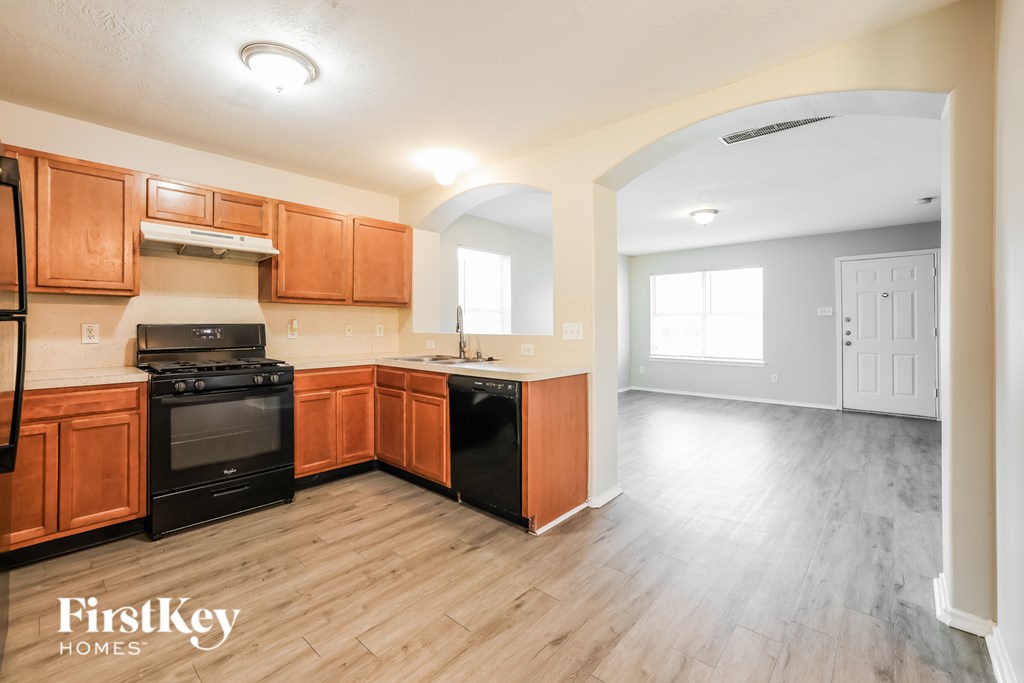 A kitchen with wooden cabinets and a black stove top oven.