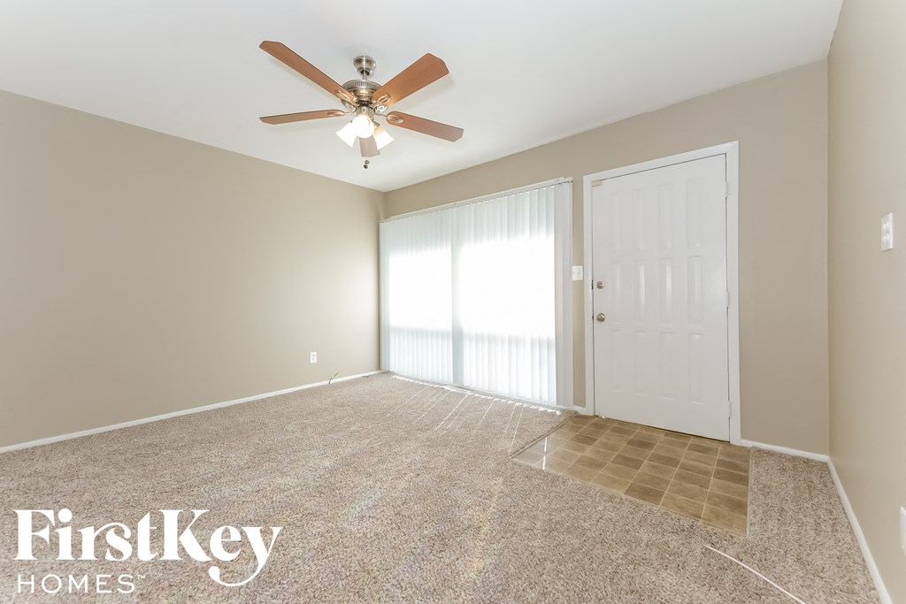 a empty living room with a ceiling fan and a window