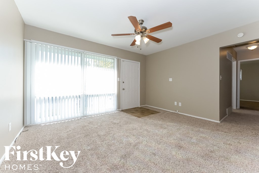 an empty living room with a ceiling fan and a window