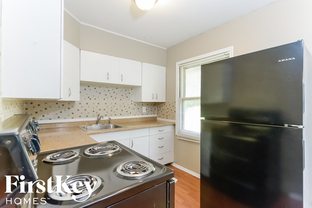 a kitchen with white cabinets and a stove and a refrigerator