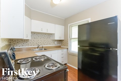 a kitchen with white cabinets and a stove and a refrigerator