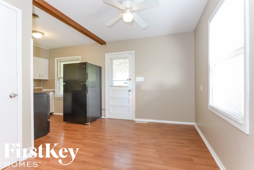 an empty kitchen with a refrigerator and a ceiling fan