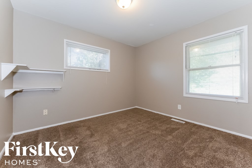 a bedroom with a carpeted floor and two windows
