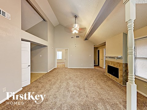 a spacious living room with a fireplace and a carpeted floor