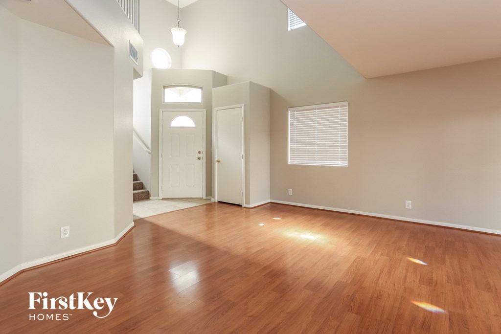A spacious room with wooden floors and a white door in the background.