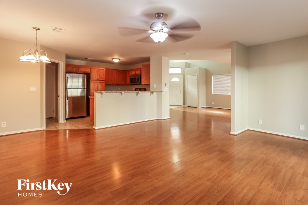 A spacious room with wooden floors and a ceiling fan.