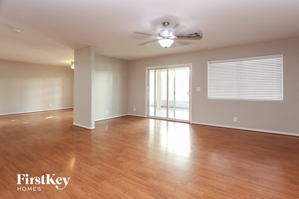 A spacious room with wooden floors and a ceiling fan.