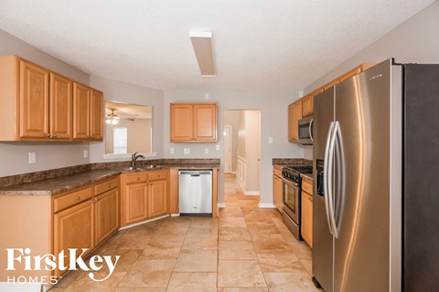 A kitchen with a stainless steel refrigerator and wooden cabinets.