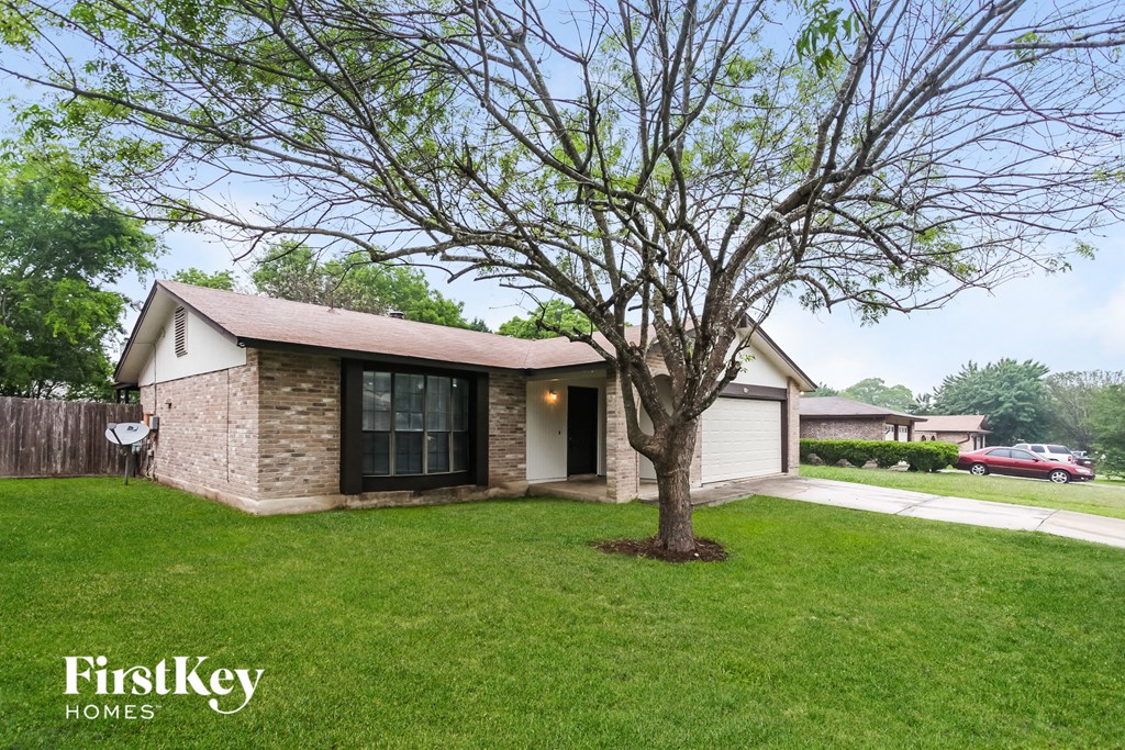 a small brick house with a large tree in the yard