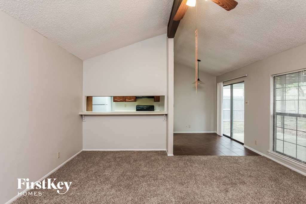 a living room with a carpeted floor and a door to a kitchen