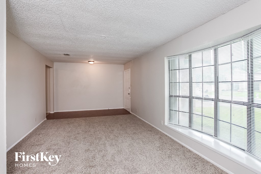 a spacious living room with large windows and carpeting