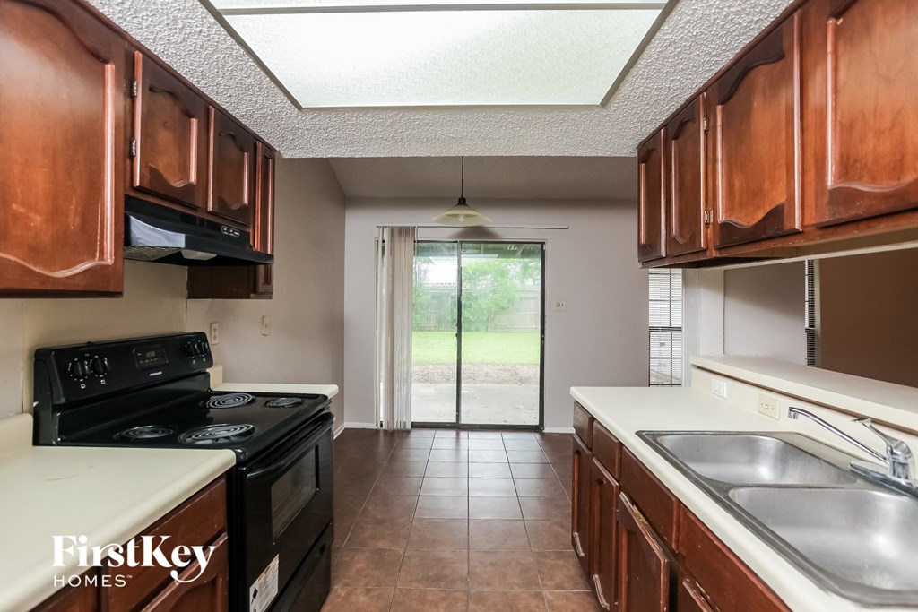 a kitchen with wood cabinets and black appliances and a sliding glass door