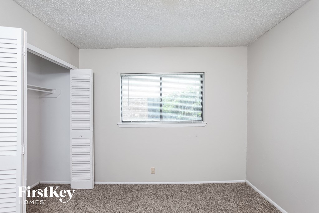 a bedroom with white walls and a window and a closet