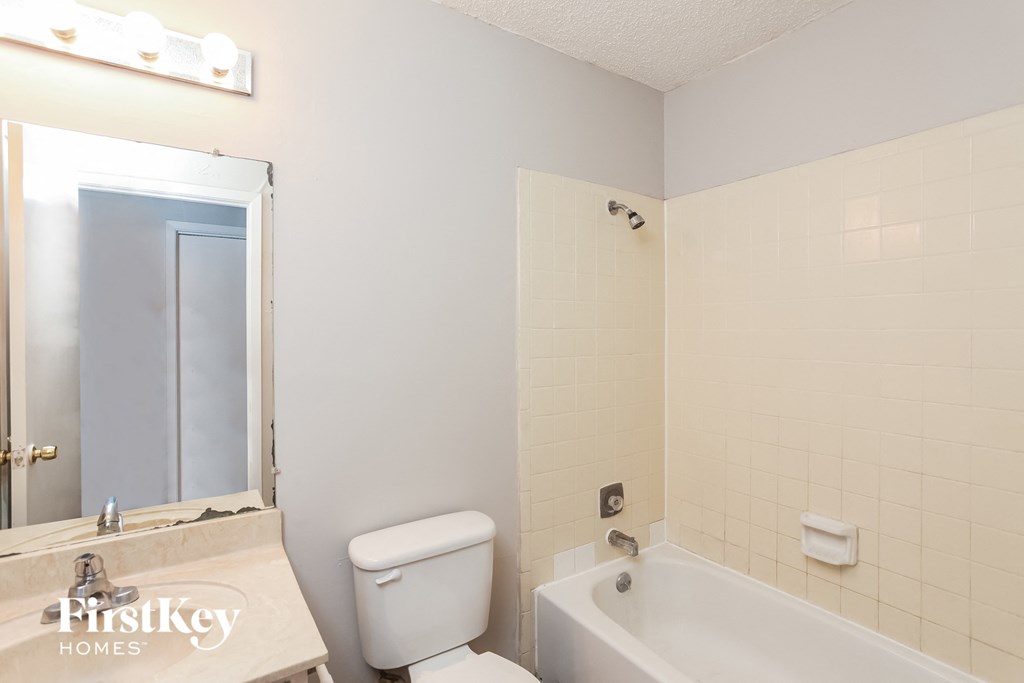 a bathroom with a toilet sink and tub and a mirror