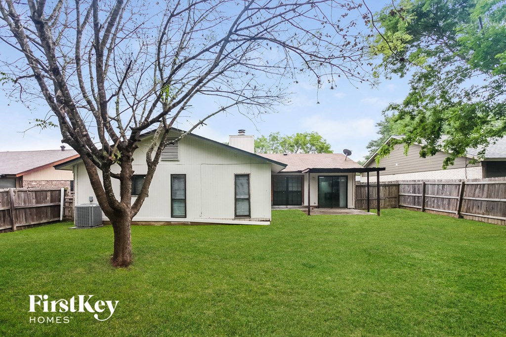 a backyard with a white house and a tree