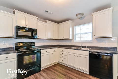 a kitchen with white cabinets and black appliances