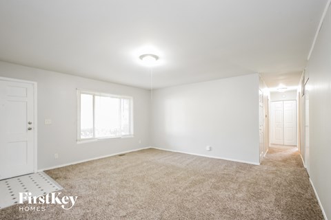 a spacious living room with carpet and white walls