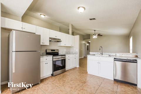 A kitchen with white cabinets and appliances.