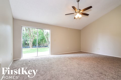 A room with a ceiling fan and a large window.