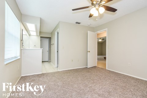 A spacious room with a ceiling fan and a carpeted floor.