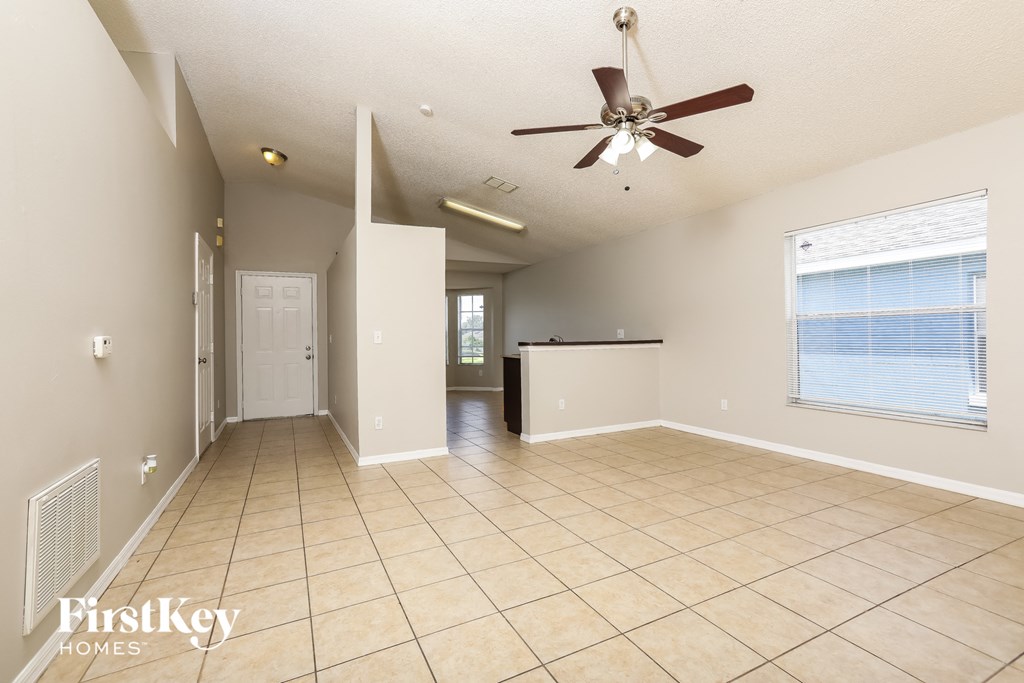 A spacious room with a ceiling fan and tiled flooring.