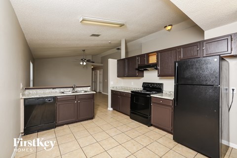 A kitchen with brown cabinets and a black refrigerator.