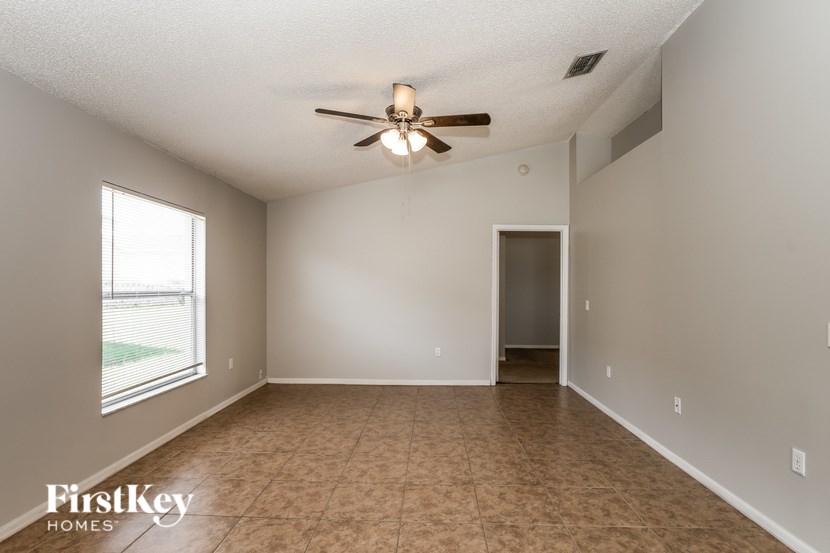 A room with a ceiling fan and a door leading to another room.